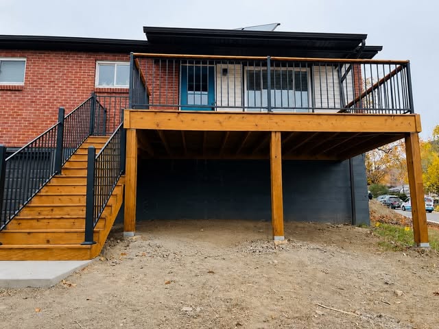 Elevated wood deck with black metal railing and a matching wood staircase