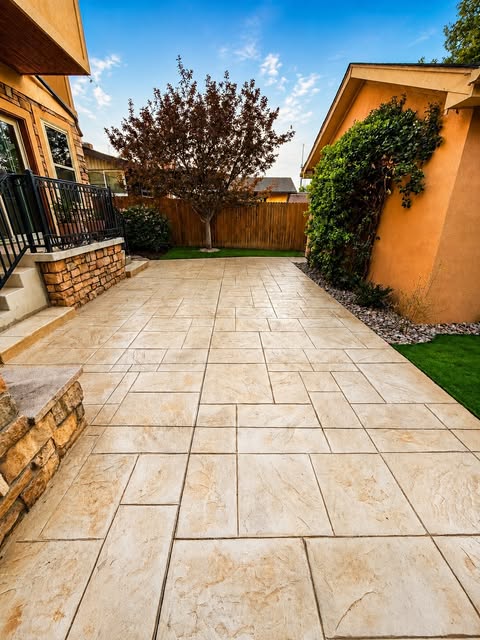 Stamped concrete walkway and patio next to a stone pillar and landscaping